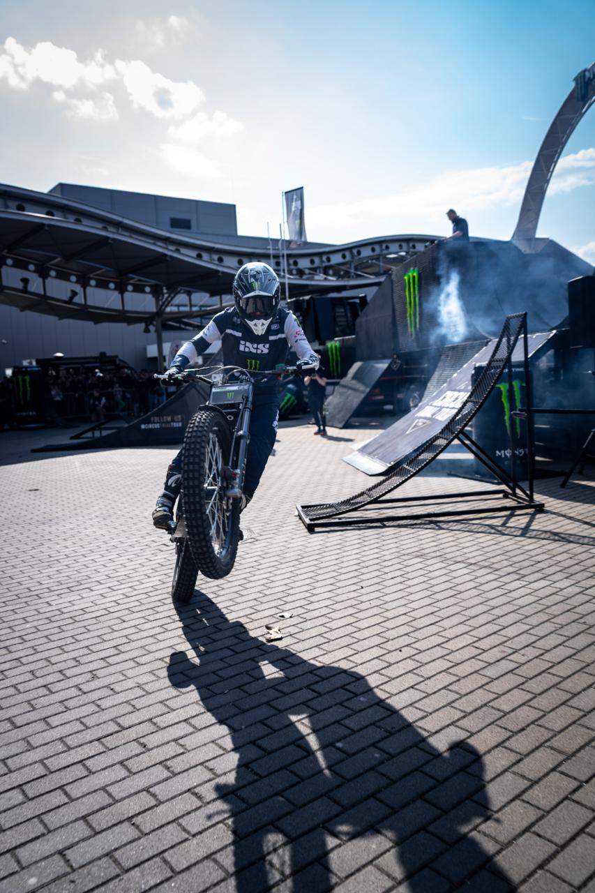 Motorbike stunt rider launching a wheelie at outdoor Monster Energy event