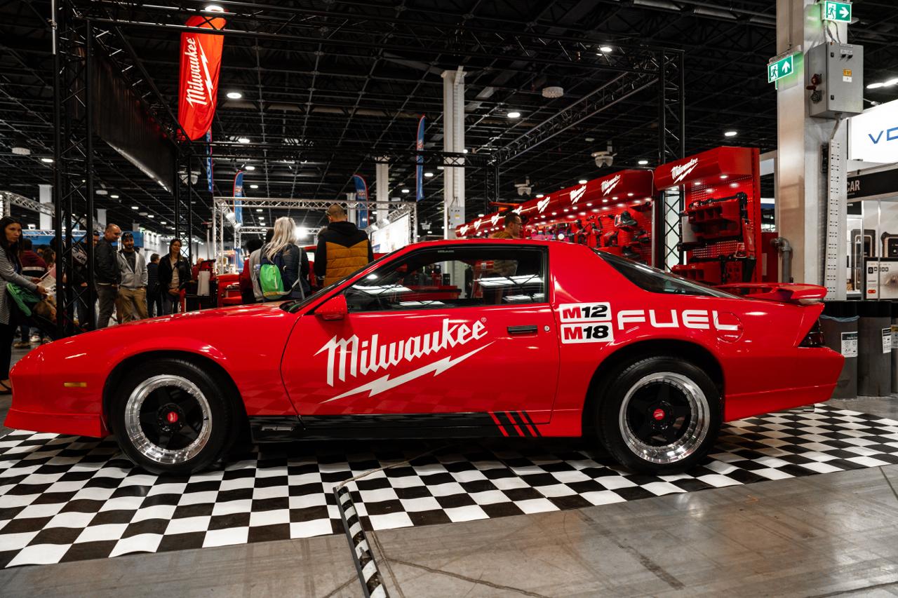 Milwaukee Tools branded red Chevrolet Camaro at indoor AMTS auto show on checkered floor