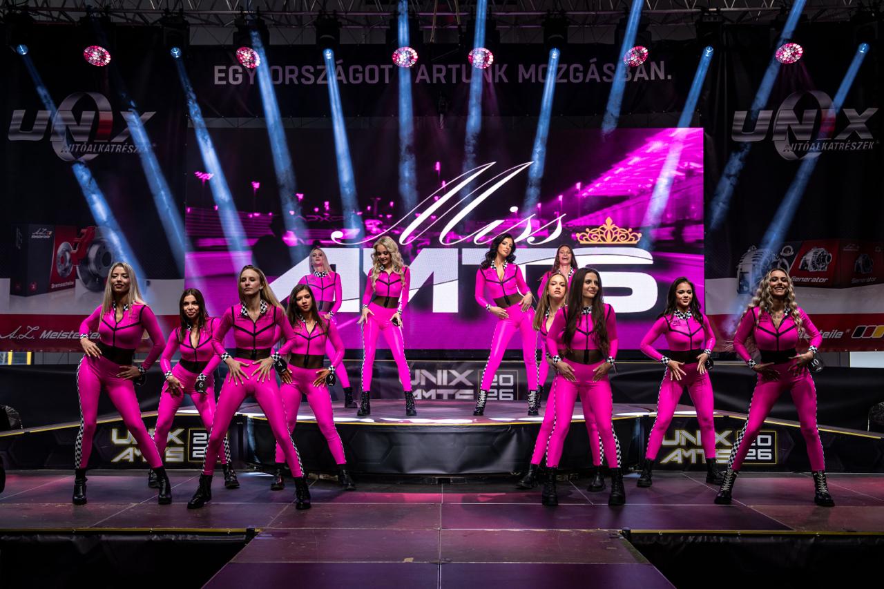 Miss AMTS stage performance with dancers in pink suits under concert beam lighting